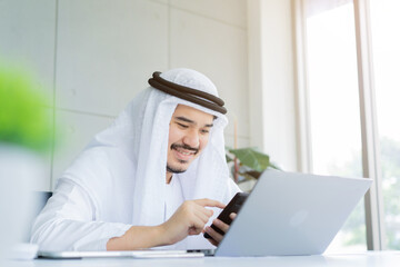 close up adult arab businessman hold smartphone to checking stock market exchange or read news on online website at office room in relax time for lifestyle business concept