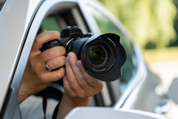 A paparazzi sits in his car and takes pictures of a famous person.  Spy with camera in the car. A...