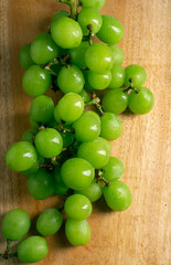 Fresh Green grapes on a wooden cutting board. Shooting in the dark. Flat lay. view from above. Bunch of grapes on a wooden grey background. Space for writing. Suitable for summer.
