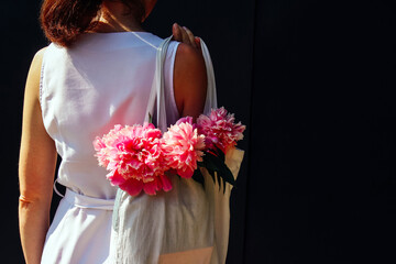 the girl holds a bag with summer flowers peonies. summer mood, lifestyle.