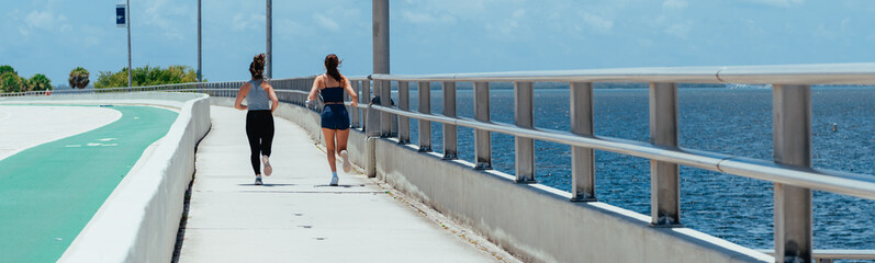 Naklejka na ściany i meble person walking on the pier bridge tow woman running sport miami lifestyle 