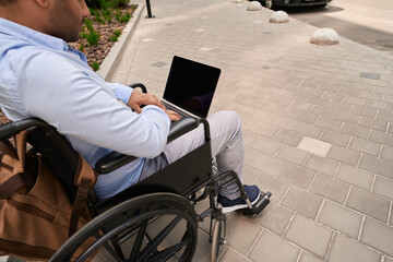 Man with disability using portable computer outdoors