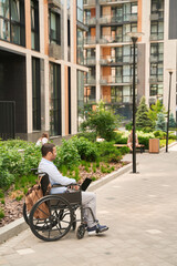 Man with laptop seated outside office building