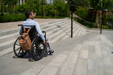 Man seated in manual wheel chair descending staircase