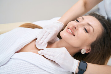 Dermatologist cleans patient skin with cotton swabs in the neck and decollete