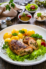 Stuffed pork minced meat with mushrooms, potatoes and greens on wooden table
