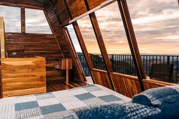 Interior of a room in a log cabin with a large window with a beautiful view. 