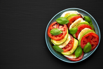 Homemade Organic Avocado Caprese Salad on a Plate on a black background, top view. Flat lay, overhead, from above. Copy space.