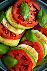 Homemade Organic Avocado Caprese Salad on a Plate on a black background, top view. Flat lay, overhead, from above.