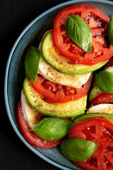 Homemade Organic Avocado Caprese Salad on a Plate on a black background, top view. Flat lay, overhead, from above. Close-up.