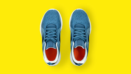 Blue sneakers close up top view. Sports shoes for running on a yellow background with copy space....