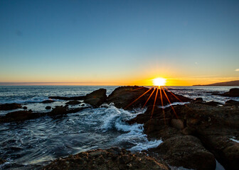 Obraz premium Sun Setting over a rock in Laguna Beach California. Waves Crashing.