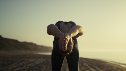 Attractive girl pulling arms back practicing bridge pose at sunset close up.
