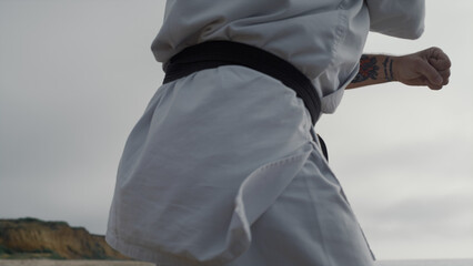 Karate fighter training martial skills on seacoast. Man practicing taekwondo.