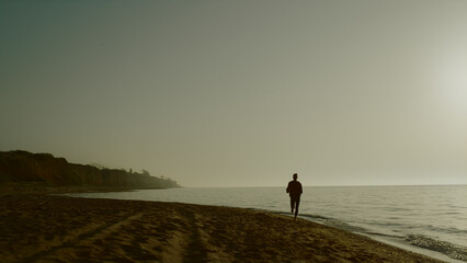 Silhouette jogger woman training on sandy beach. Sportswoman running seacoast.
