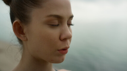 Closed eyed girl meditating on beach close up. Woman breathing practicing yoga.