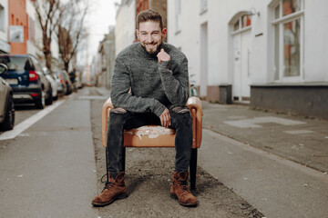 happy man on chair sit in cold city und smile joyful at camera