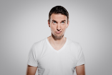 Obraz premium bored and annoyed face expression of man while look at camera and show his inner feelings and emotion with eyes and glimpse isolated on gray background
