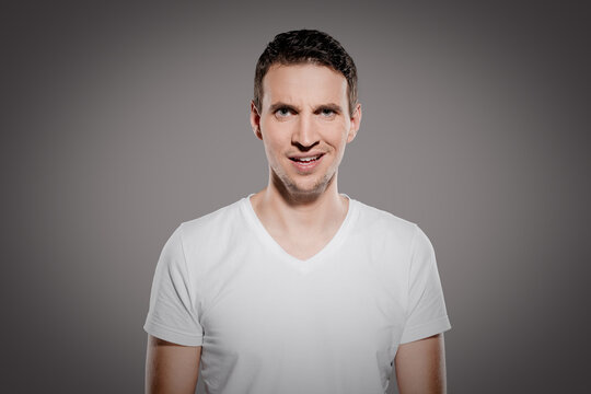 stupid and mindless face expression of man while look at camera and show his questioning  emotions with eyes and glimpse at camera isolated on gray background
