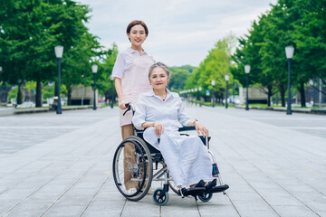 車椅子の女性と介護するエプロン姿の女性