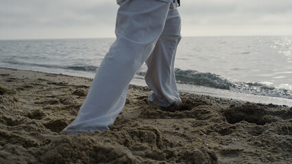 Closeup man feet stepping on sand training karate. Athlete exercising on beach. © stockbusters