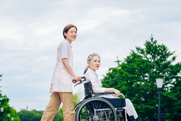 車椅子の女性と介護するエプロン姿の女性