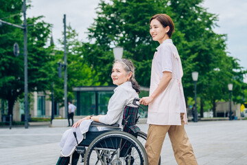車椅子の女性と介護するエプロン姿の女性