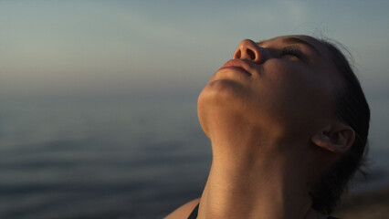 Relaxed girl bending neck standing plank pose on beach closeup. Woman stretching