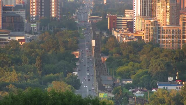 Kiev, Ukraine - 30.06.2022: Time-lapse road wiev. Cars, metro trains and people moving of sity road. Video shoving faster life. In the green forest