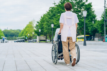 車椅子の女性と介護するエプロン姿の女性