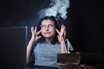 girl sits in front of the monitor and thinks hard, smoke comes out of her head, concept on a black...