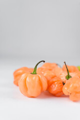 A scotch bonnet pepper with stem on a white background, fresh pepper, orange coral pepper, Nigerian scotch bonnet pepper