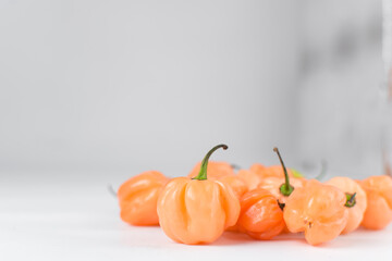 A scotch bonnet pepper with stem on a white background, fresh pepper, orange coral pepper, Nigerian...