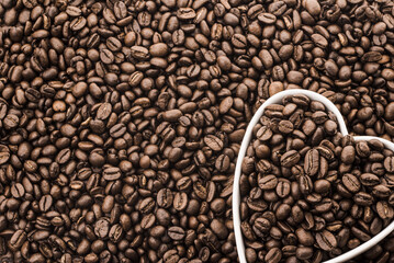 Coffee Beans in White Heart Shape Plate on Fresh Coffee Beans Background.
