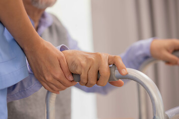 Close up.Asian nurse holding an elderly man with a walking stick for physiotherapy.