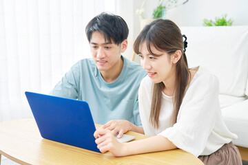 ノートパソコンをリビングで使うカップル