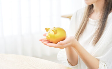 リビングで豚の貯金箱を持つ女性の手元