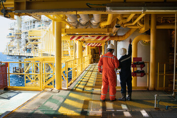 Male workers inspect long steel pipes and pipe elbows in oil and gas stations between oil and gas...