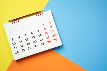 close up of calendar and pencil on the colorful table background, planning for business meeting or travel planning concept - obrazy, fototapety, plakaty