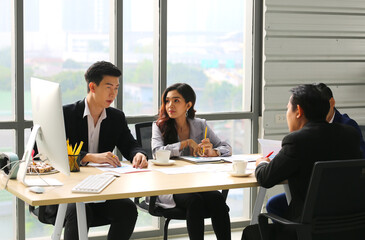 Group of young modern people in smart casual wear communicating and using modern technologies while working in the office