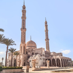 A young adult girl wearing a hijab and an Islamic dress stands in front of the Al Mustafa Mosque in Sharm El Sheikh, Egypt. Egyptian Muslim temple with two minarets against the blue sky
