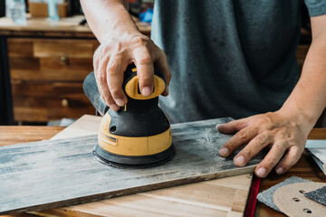 carpenter use random orbit sander or palm sander polishes wooden in the workshop ,DIY maker and...