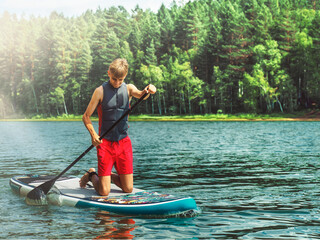 Teenager on a SUP board rakes a wave with an oar. SUP surfing. The concept of an active lifestyle.