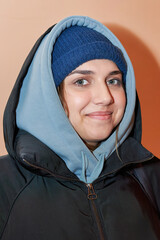 Facial portrait of a pretty girl in a hat and dark jacket with a hood - 516110505