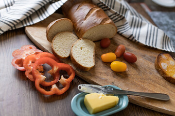 Still life on the kitchen table with vegetables and bread and butter cut into a baguette.