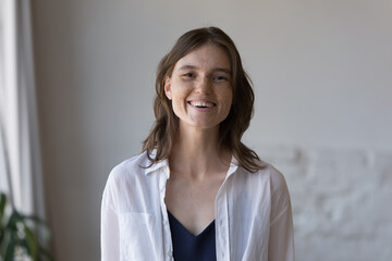 Cheerful woman with nice freckles on cute face smile staring at camera, standing pose in domestic...