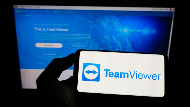 Stuttgart, Germany - 01-16-2022: Person holding smartphone with logo of German technology company TeamViewer AG on screen in front of website. Focus on phone display.