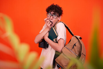 Young attractive tourist with a backpack. Orange background.	