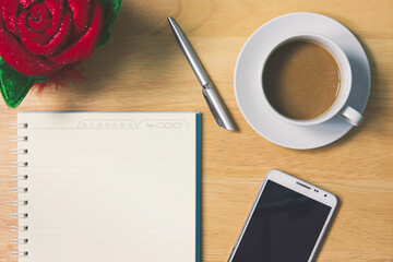 Simple workplace with a cup of coffee, notebook paper, pen, smartphone and glasses on wood table