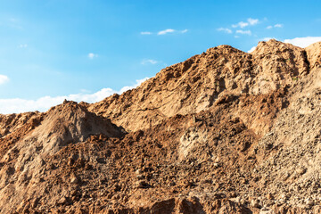 Heap of earth sand and clay at the construction site against the sky. Earthworks at the construction site.